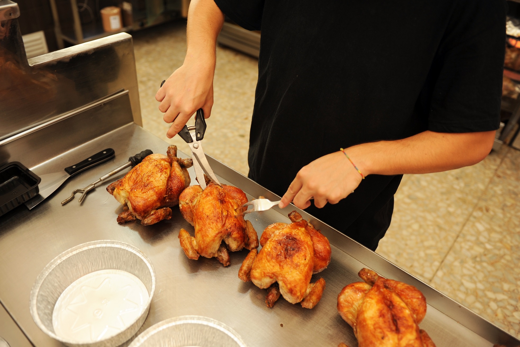 Chicken rotisserie employee preparing chickens for orders.