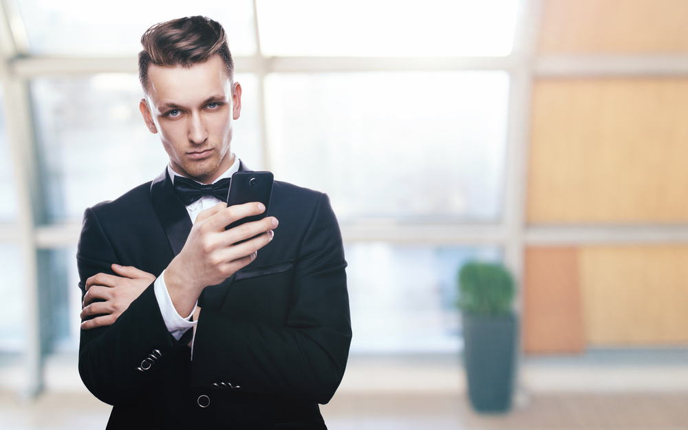 Angry groom at wedding looking at his phone