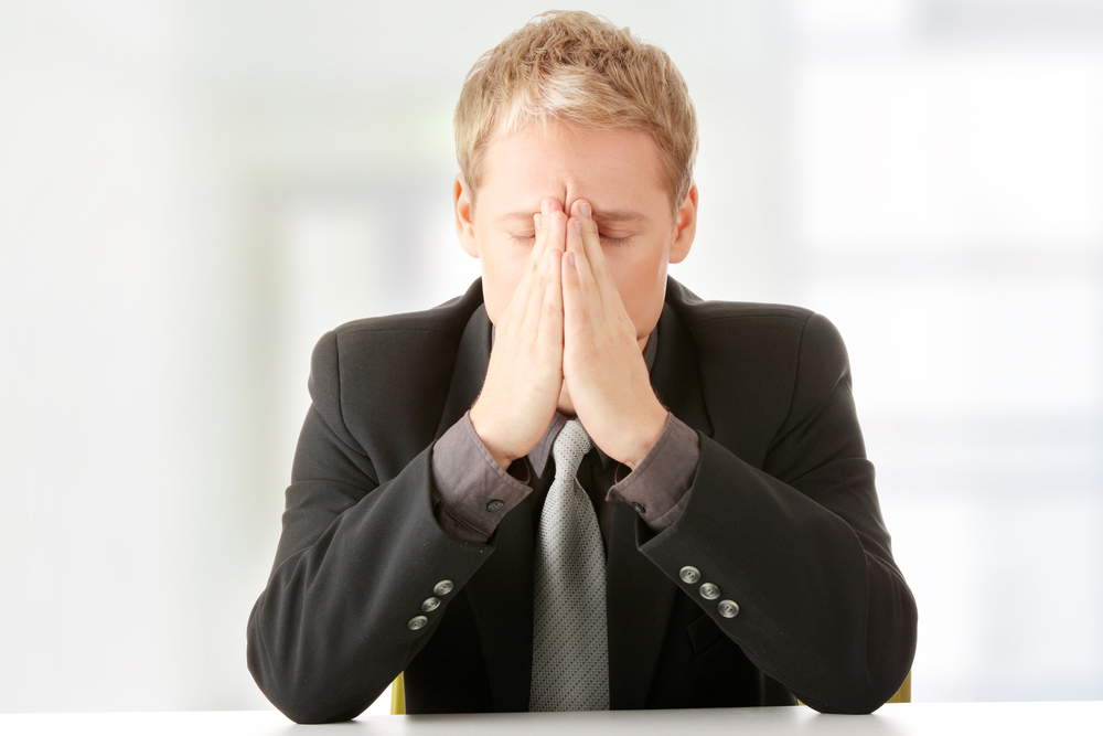 Young businessman sitting behind the desk and being worried