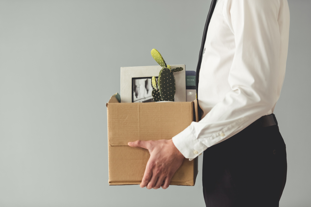 Cropped image of handsome businessman in formal wear holding a box with his stuff and leave after being fired