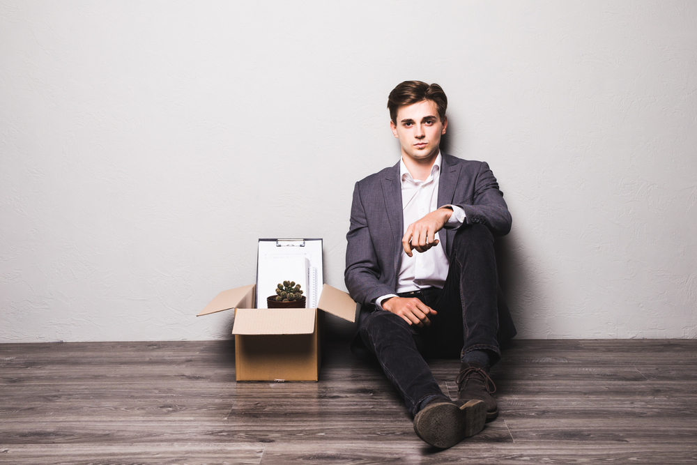 Sad fired businessman sitting outside meeting room after being dismissed