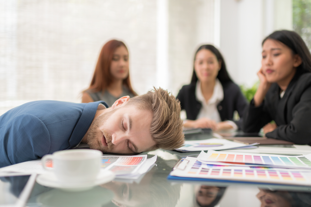 Person in blue shirt sleeping in the conference room during a meeting
