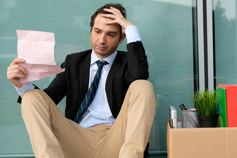 Fired male employee reading the notice of job termination