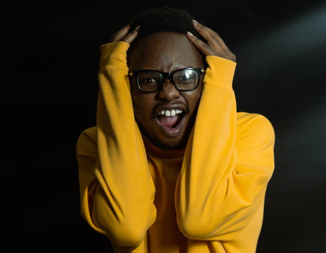 Upset man wearing yellow hoodie and glasses.
