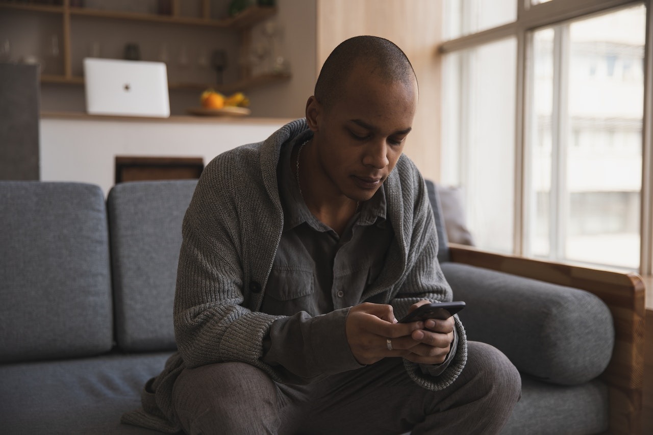 Man seating on the sofa and texting on his phone.