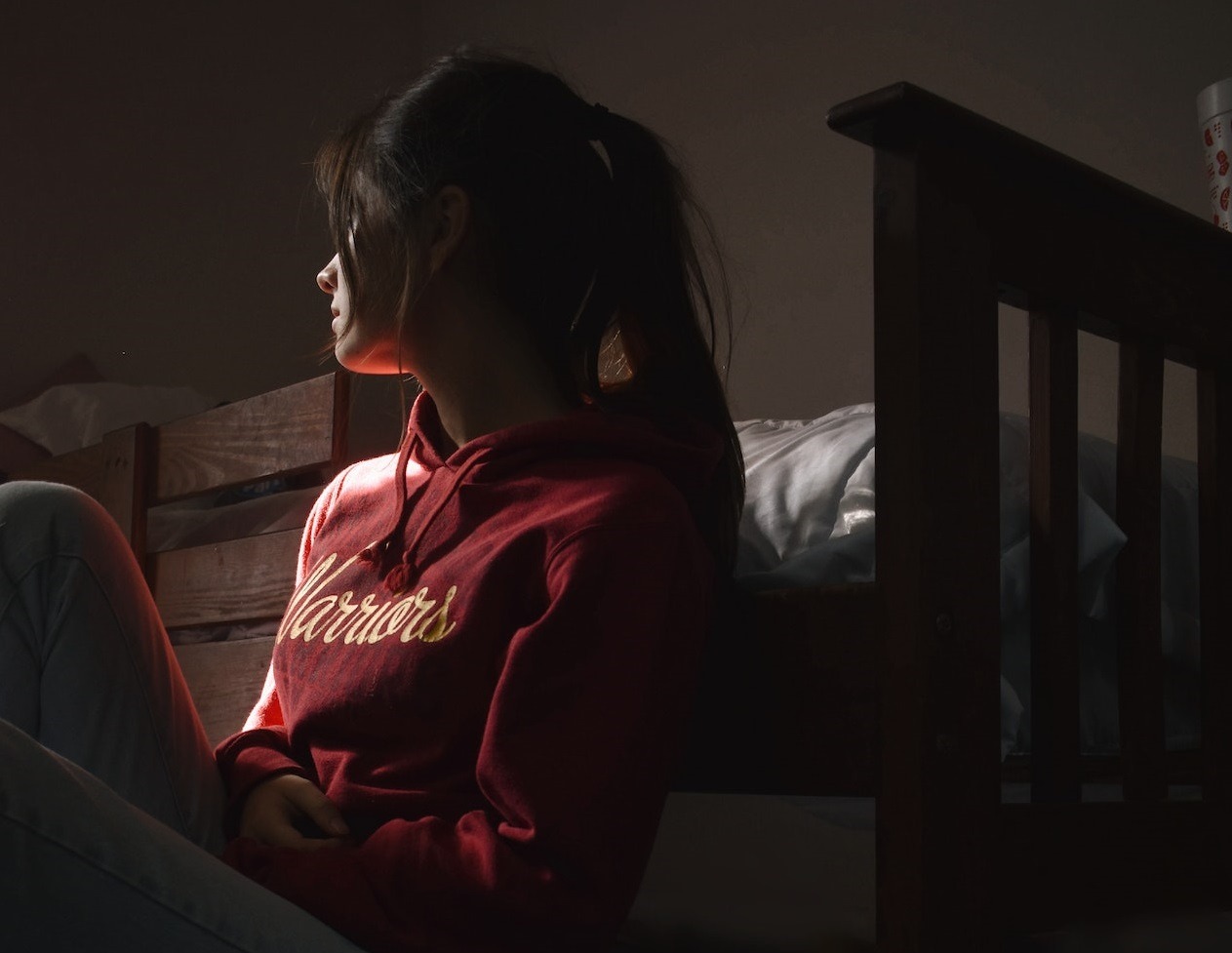 Woman seating on the floor in the dark room.