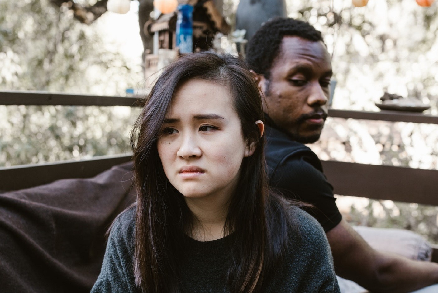 A man looking at woman from behind with sad face seating on the sofa.