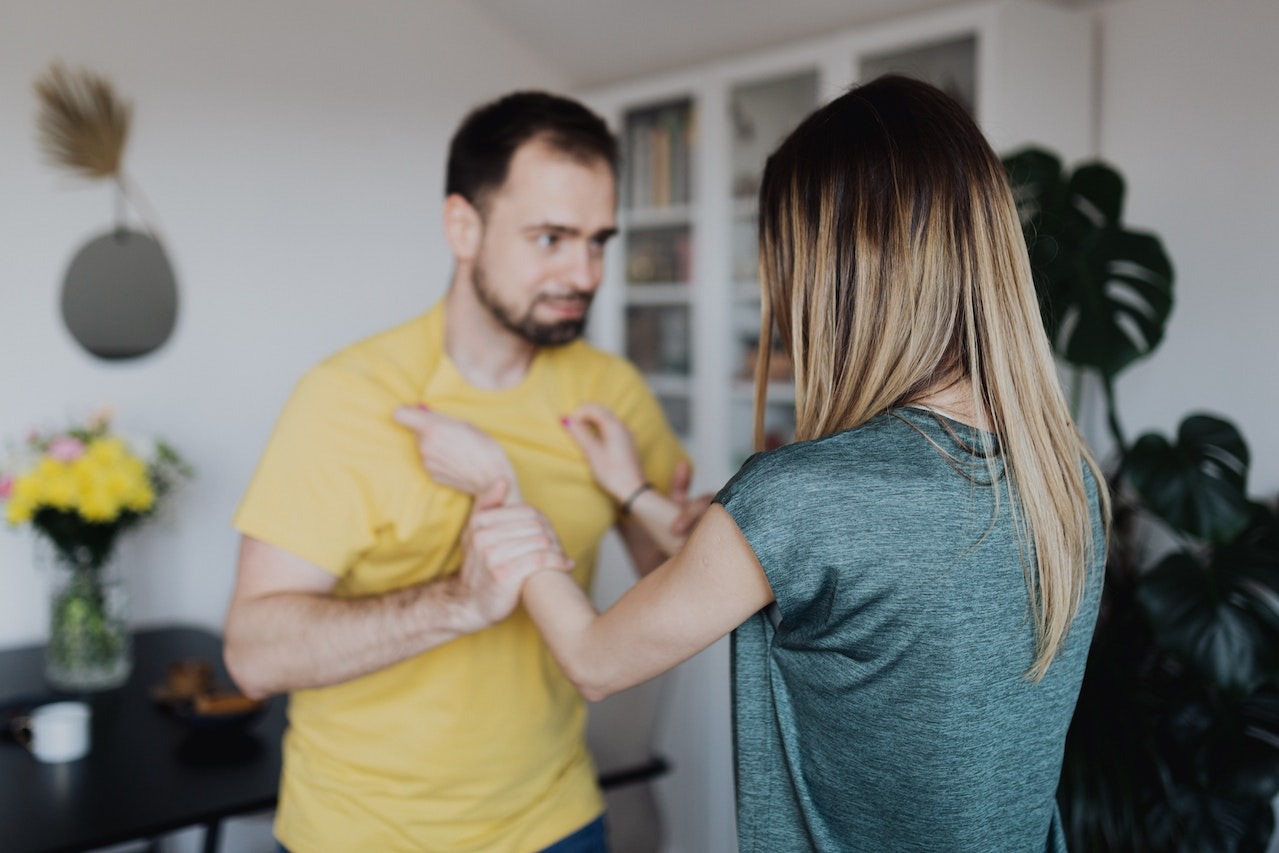 Man pushing a woman inside a room.