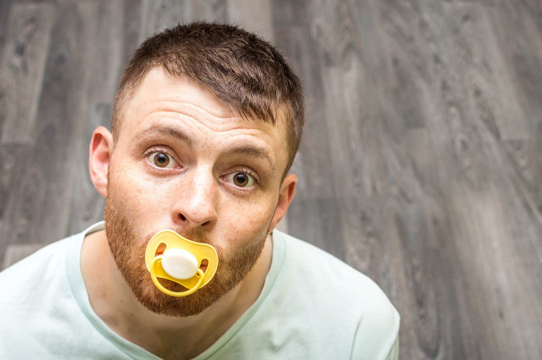 Adult man with a baby pacifier in his mouth.