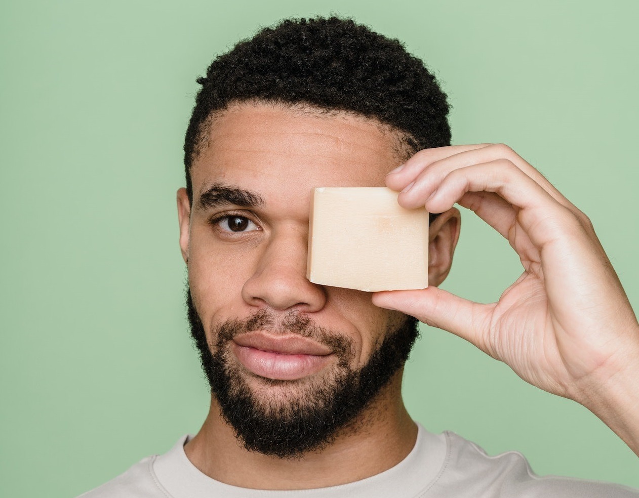 Black man holding a soap on his face.