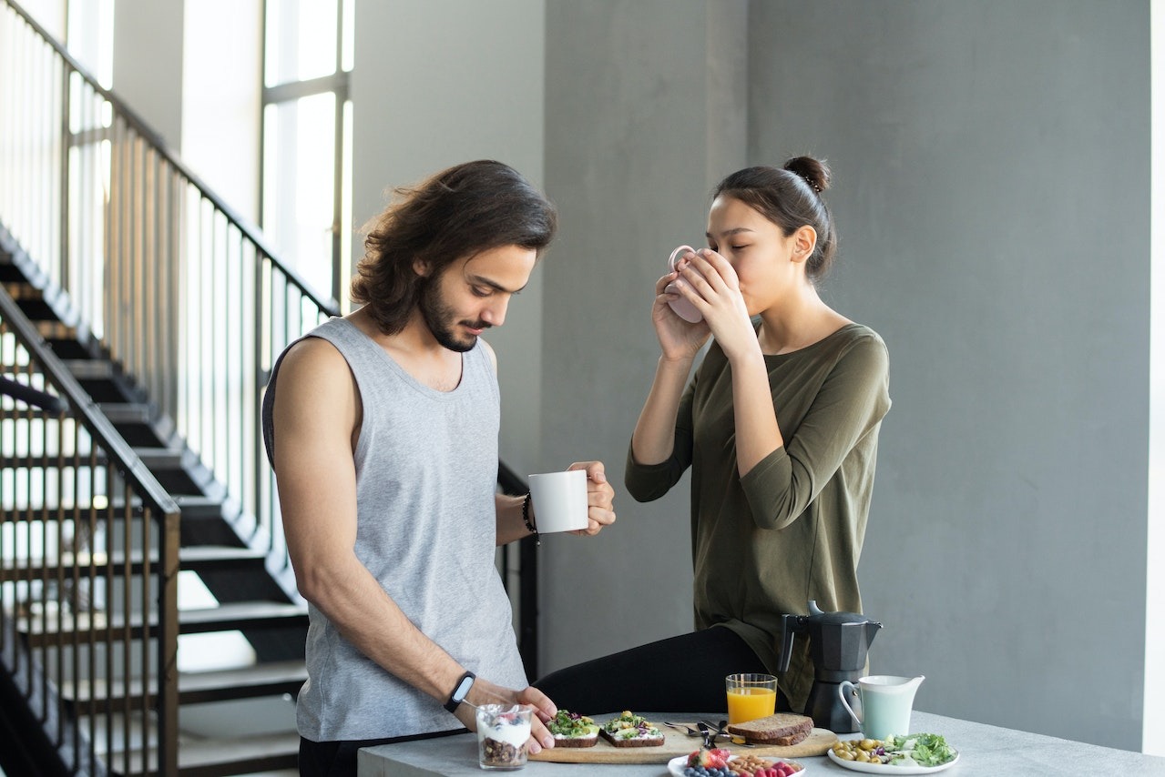 Man eating and talking with a woman drinking coffee.