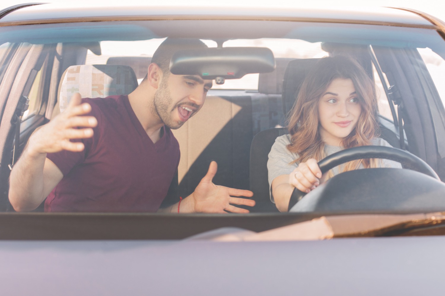 Man screaming to a driving woman inside a car.