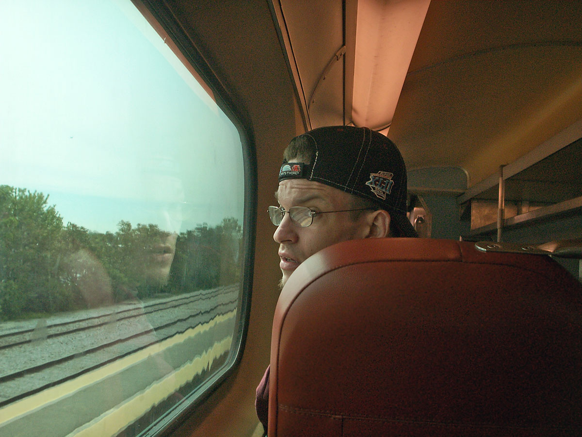 Man is traveling by train ,looking outside.