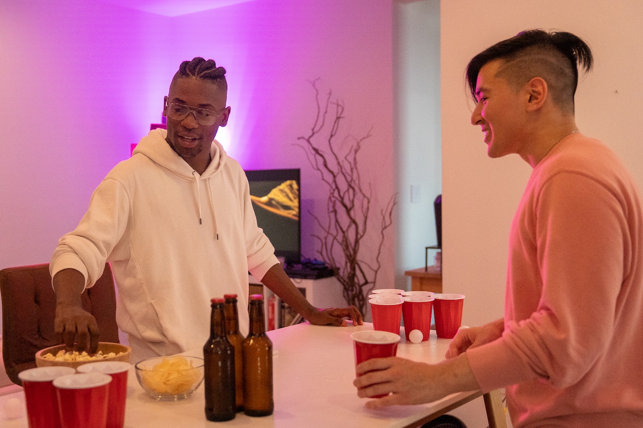 Black man is having party with other man holding a cup.