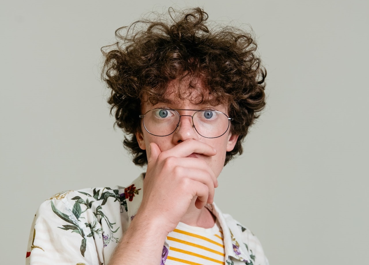 Young man is looking at camera with surprised face.