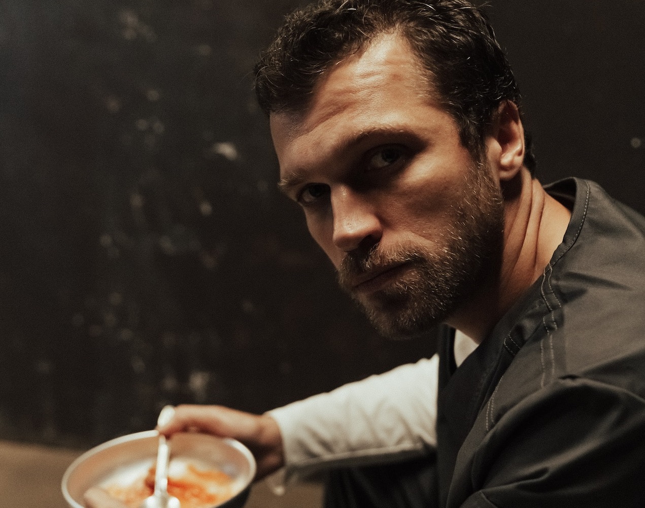 A man wearing black and white uniform is holding a bowl of food.
