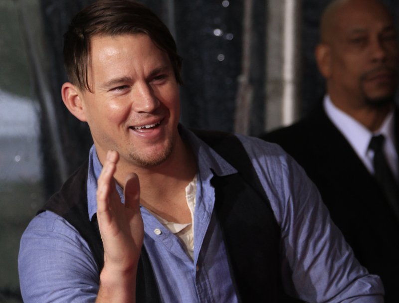 Channing Tatum in blue shirt and a vest waving to the fans