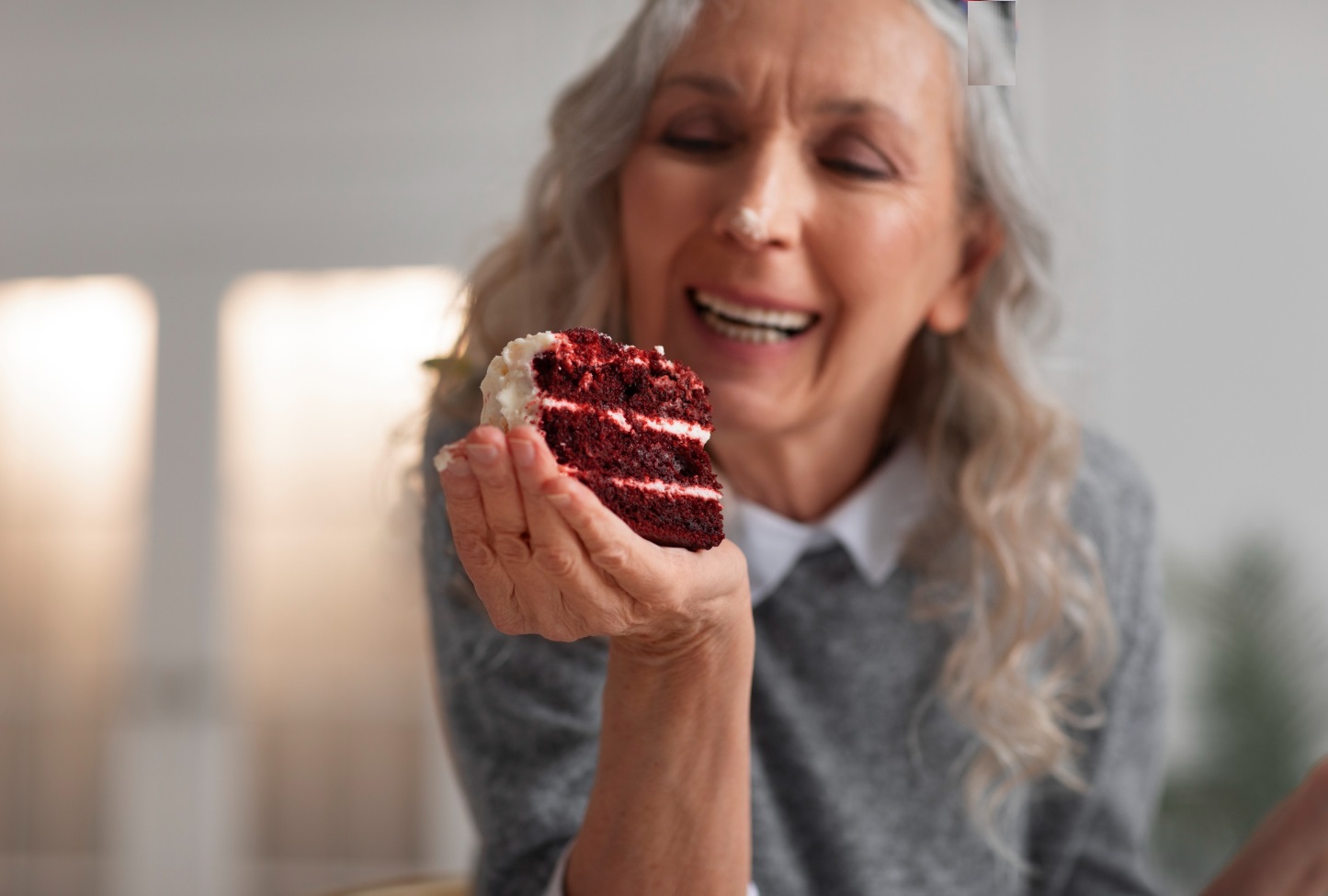 Woman is holding a piece of chocolate cake in her hand and smiling.