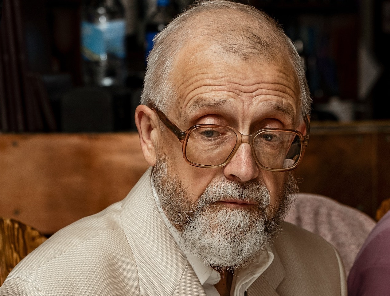 Elderly man is sitting at dining table in restaurant.