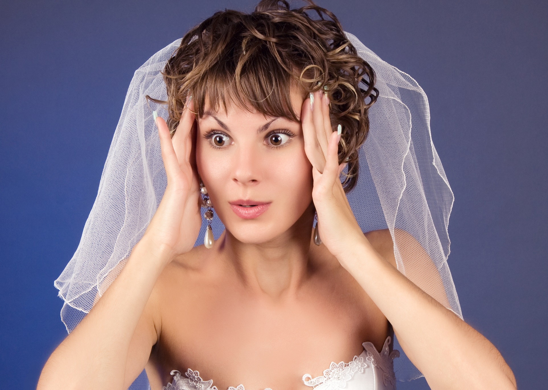 Woman wearing wedding dress is looking shocked.