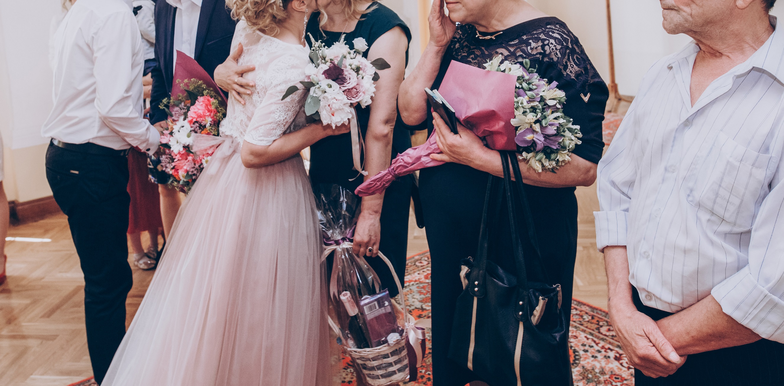 Family and guests congratulating bride and groom with presents and flowers.