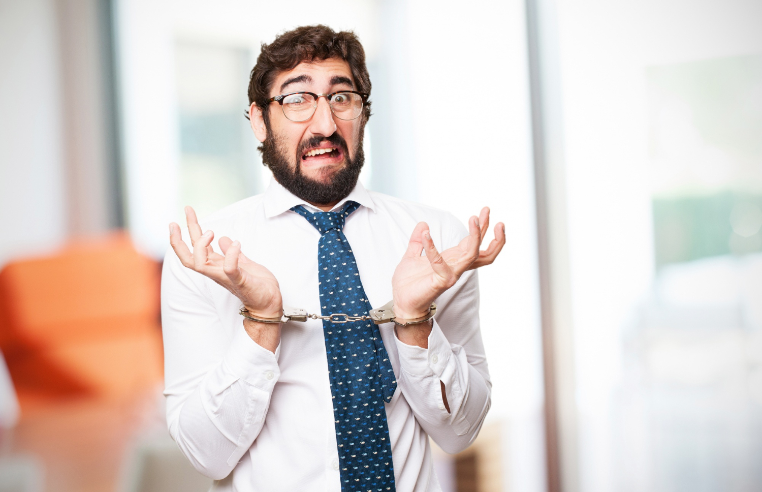 Man is wearing handcuffs and looking shocked.