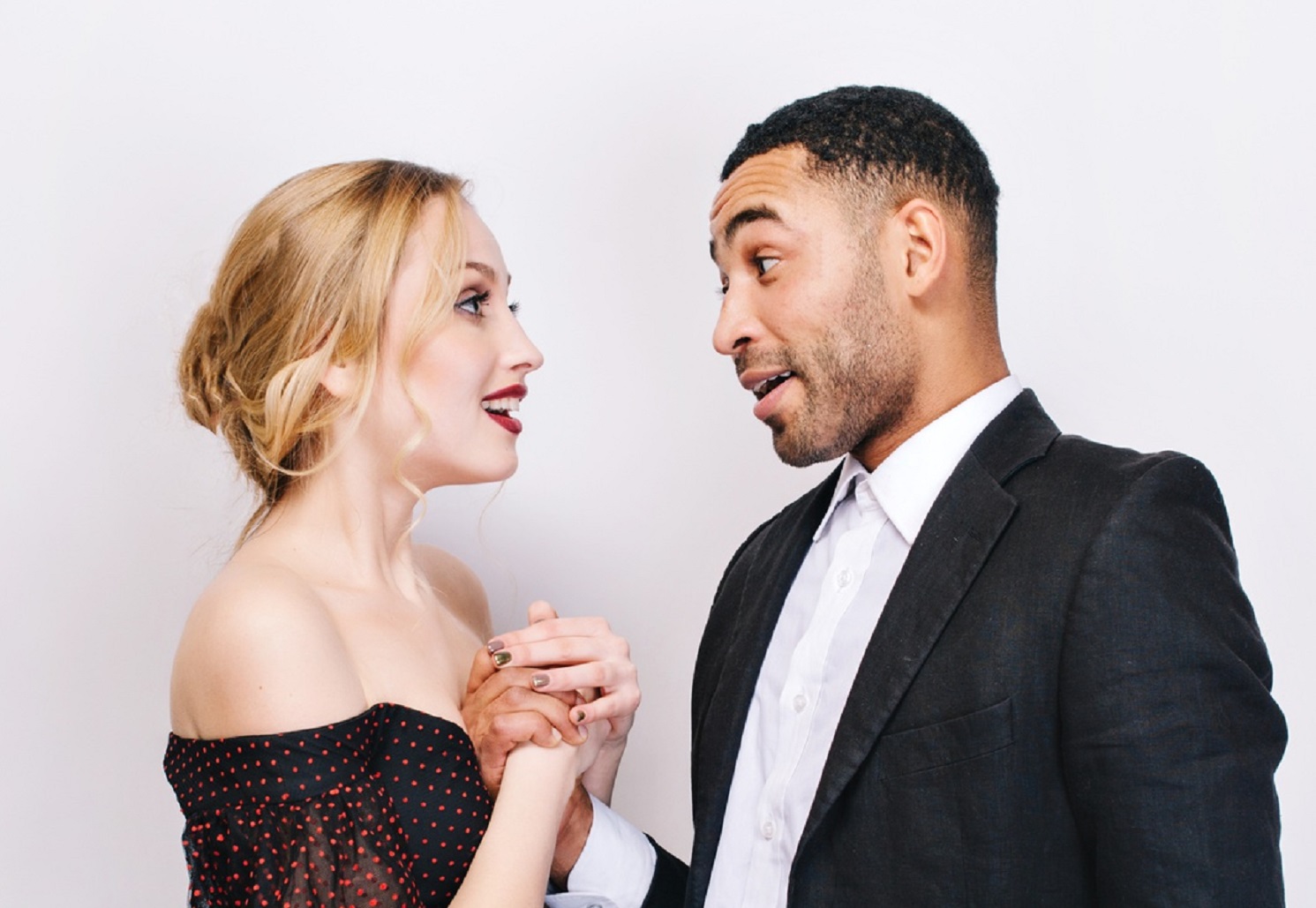 Man in black suit is talking to a woman who is looking surprised.