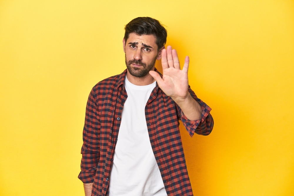Caucasian man in red checkered shirt refusing something