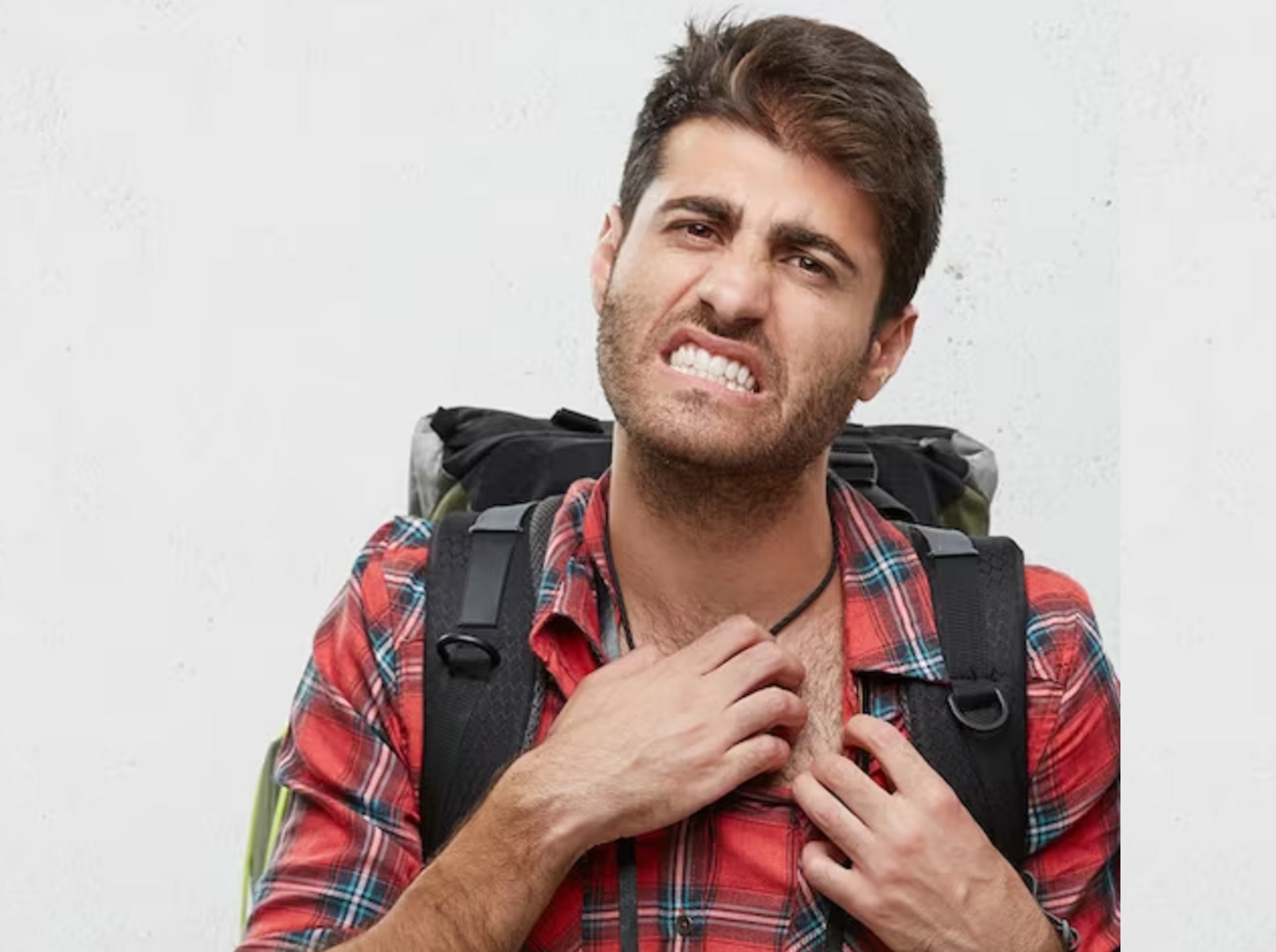 Man is panicking from insect bites on grey background.