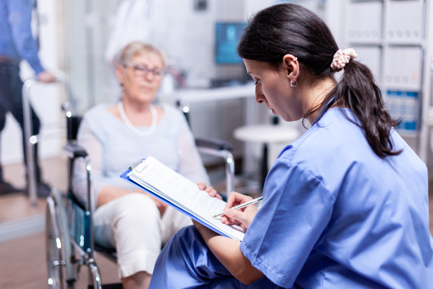 A nurse is writing prescription to disabled woman in wheelchair.