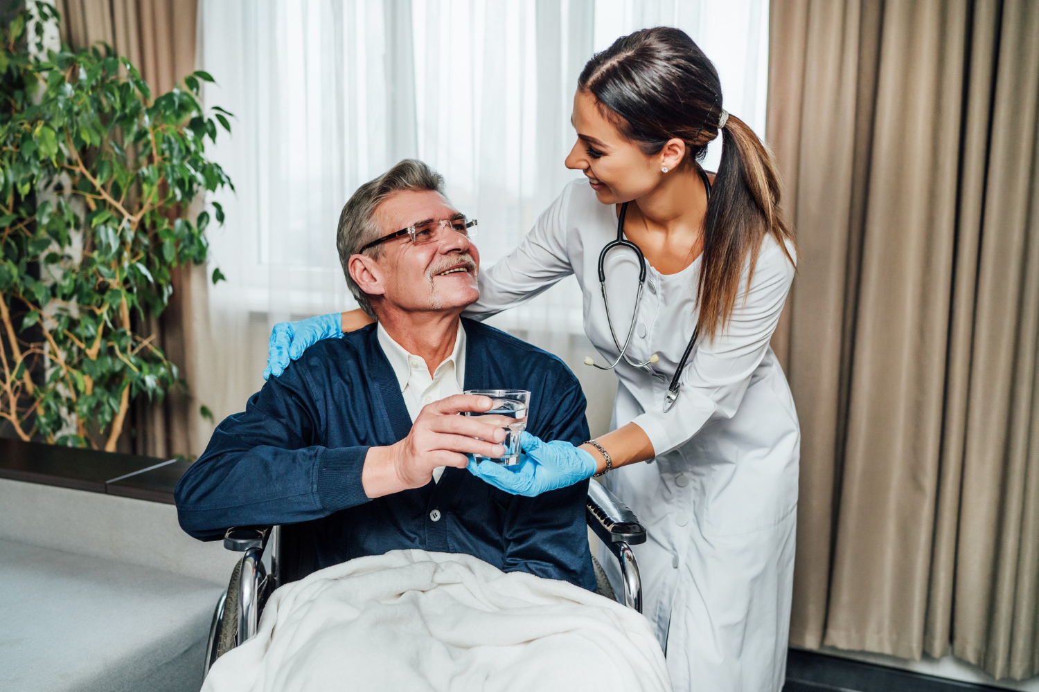Photo an older man in a wheelchair smiles at the nurse assistant.