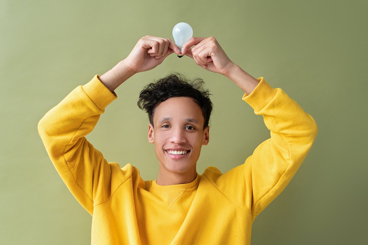 Young man is holding a light bulb above his head.