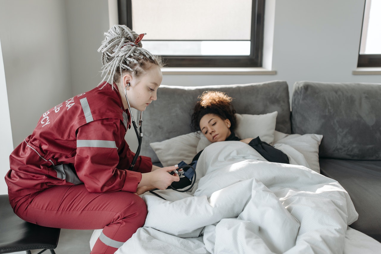 Paramedic is checking on a black woman laying in bed.