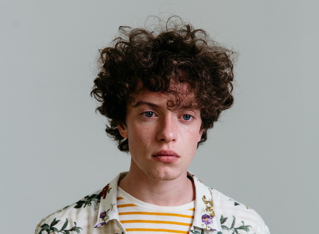 Photo of a man wearing shirt crying with tears.
