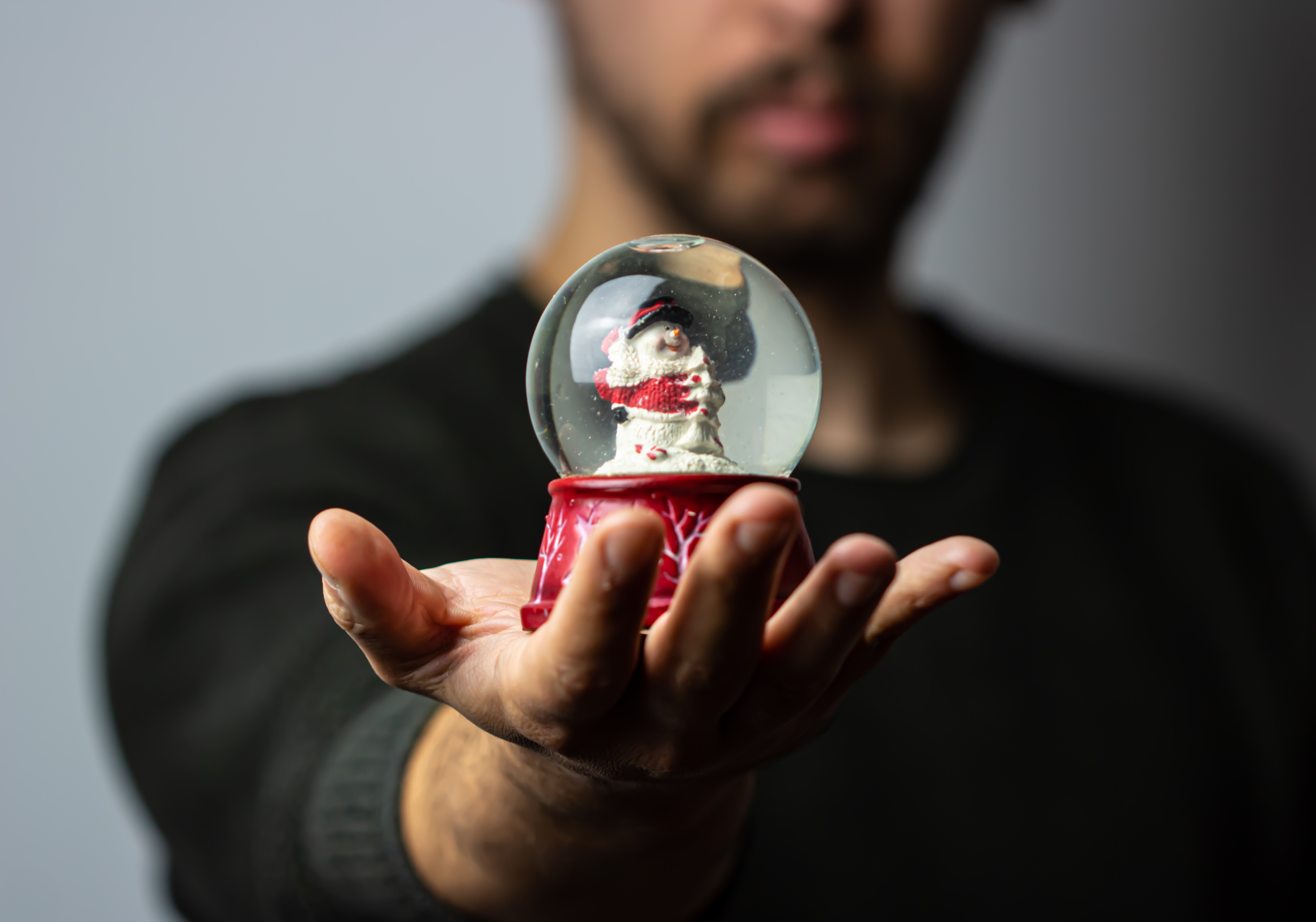 A man is holding a Christmas snow globe in his hand.