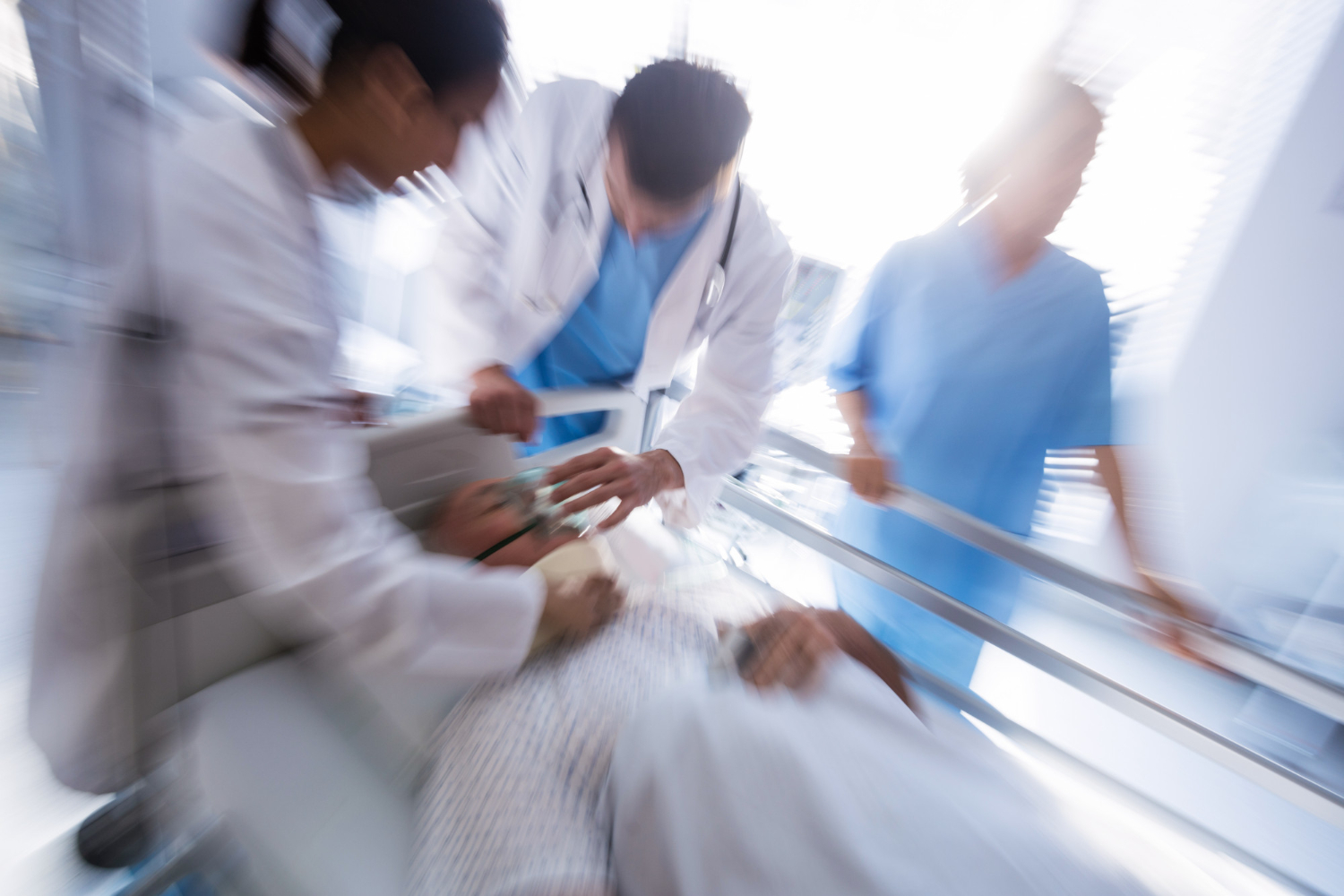 Man laying on stretcher with team of doctors putting oxygen mask on his face.