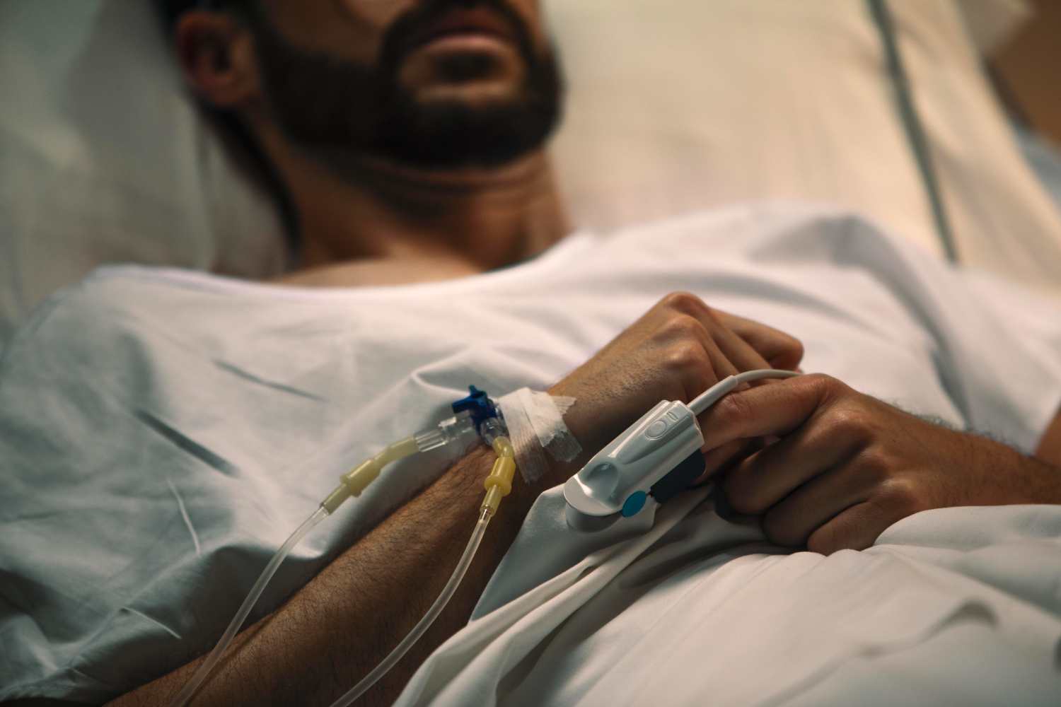 Photo of man with beard is laying in hospital bed.