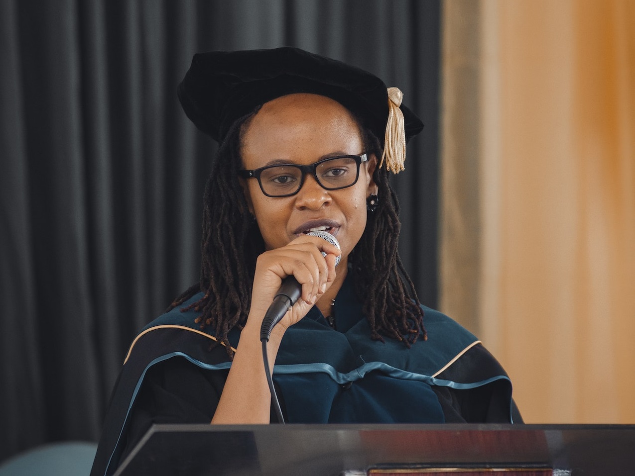 Young woman in a graduation gown is giving a speech.