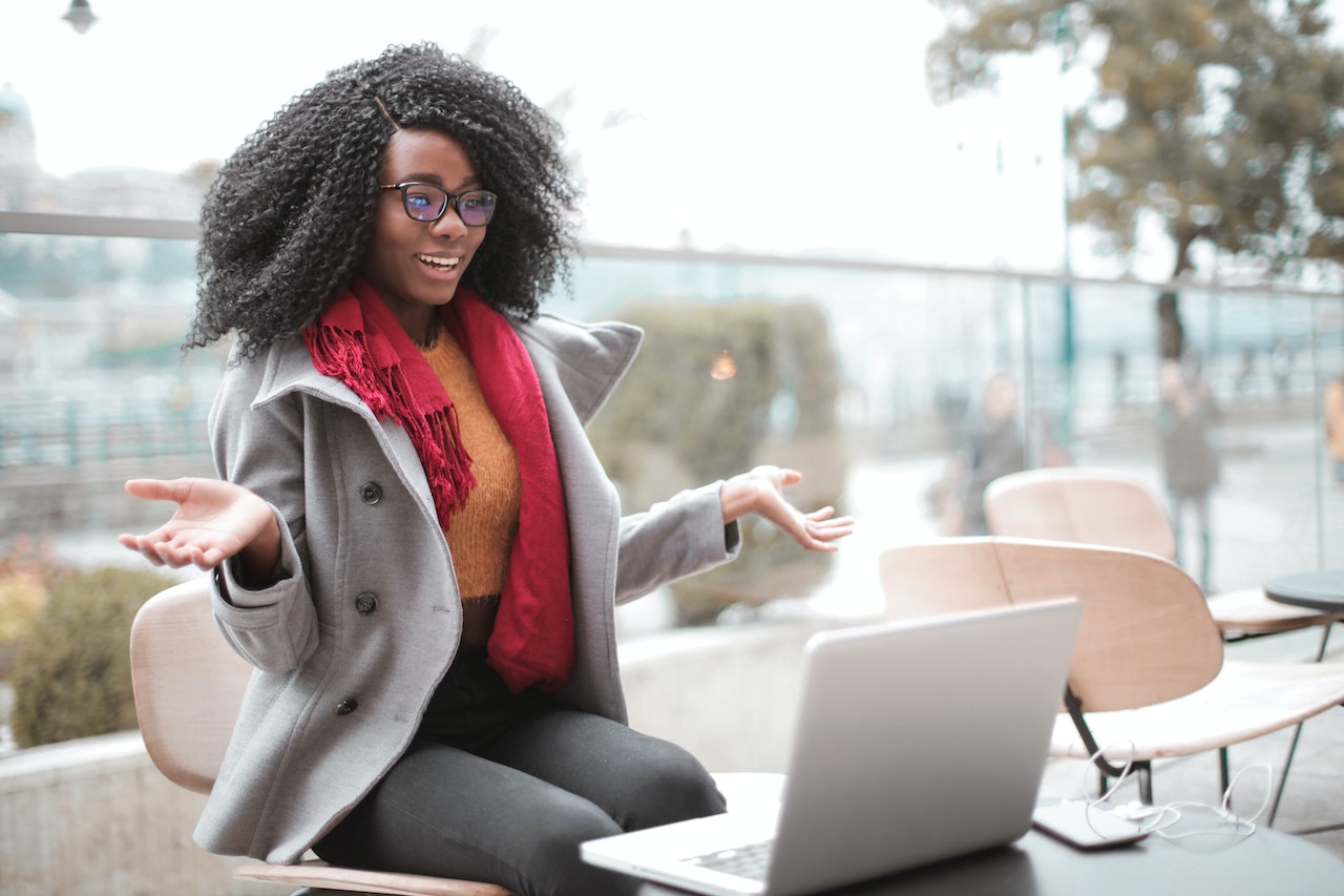 Surprised woman is sitting with laptop and smiling.