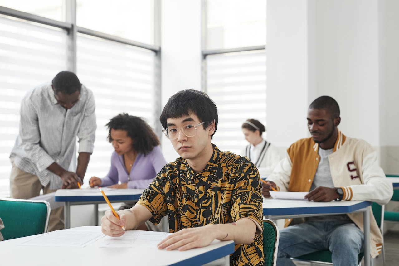 A young man sitting inside the classroom and taking an exam.