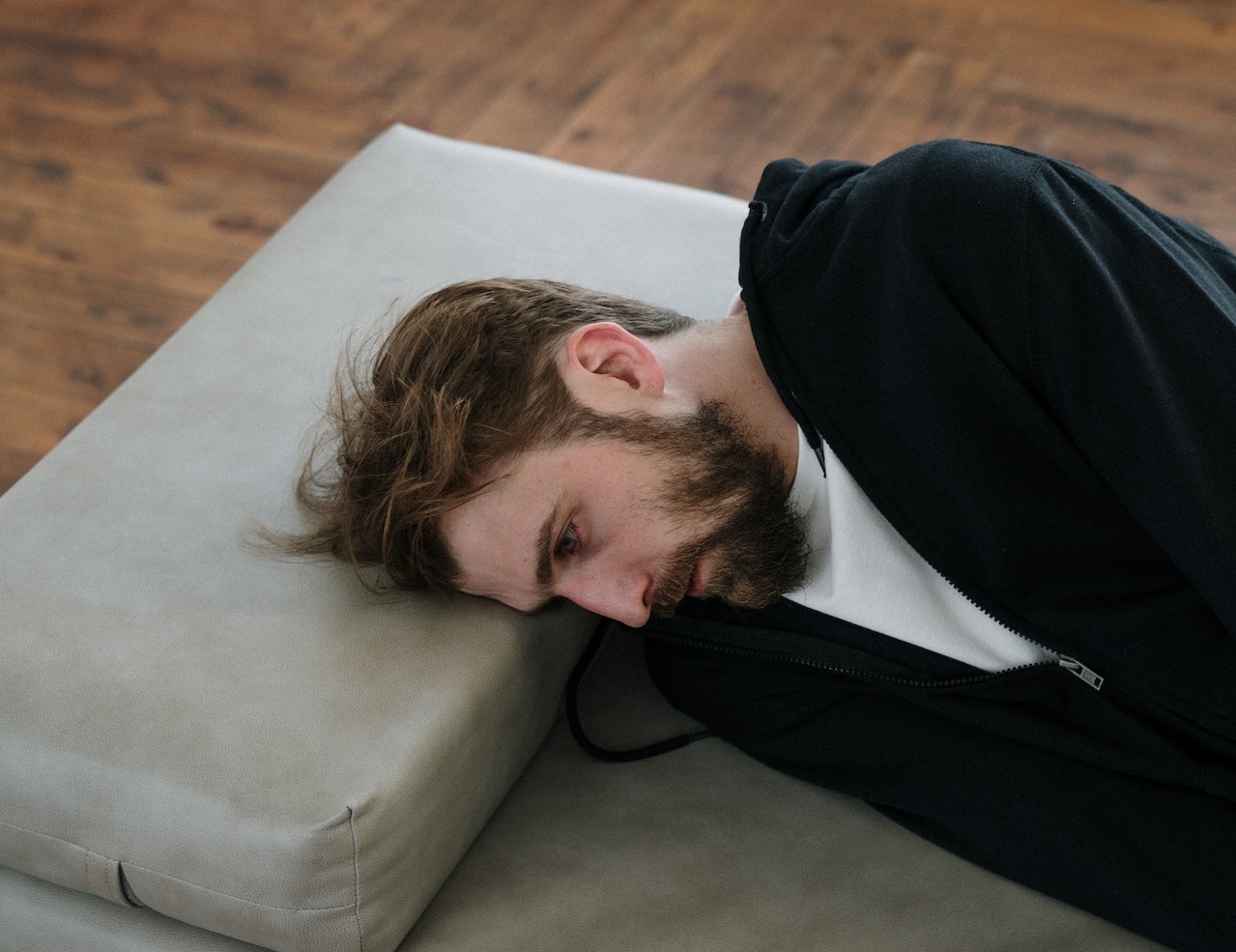 Man lying on gray couch ,thinking and looking sad.