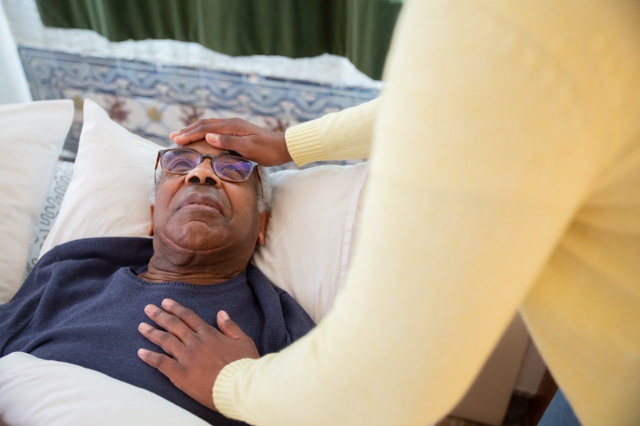 Man laying on the bed is talking with other person wearing yellow sweater.