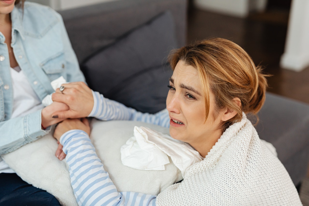 Woman in a striped shirt crying on the pillow and looking at side.
