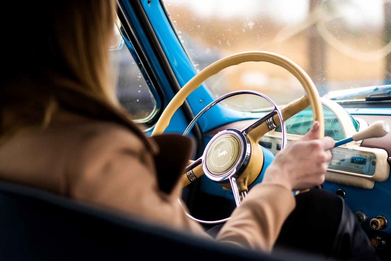 Close up photo of woman driving an old car.