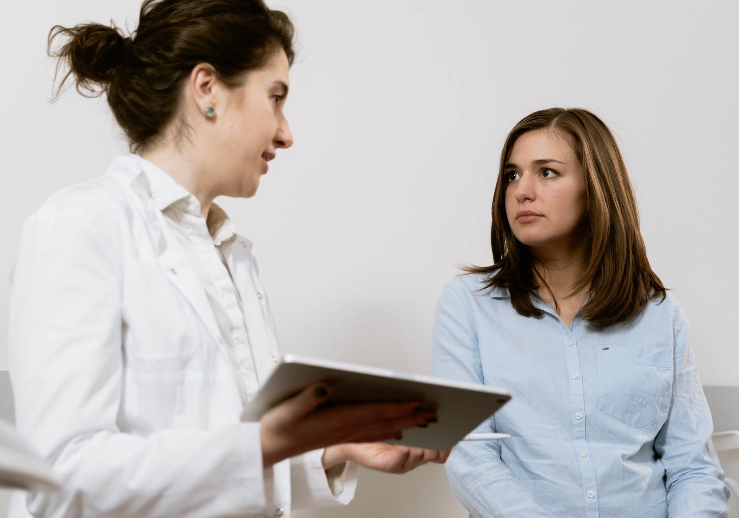 Young woman is talking with a female doctor in hospital.