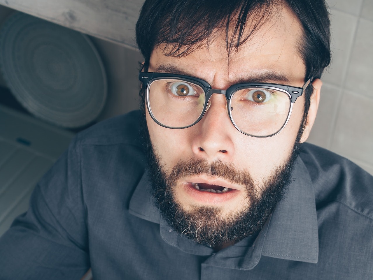 Bearded man is looking up surprised.