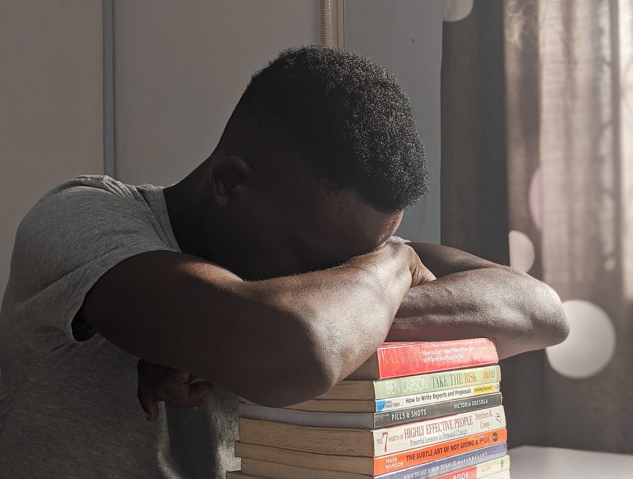 Young black man is slipping on books at school desk.
