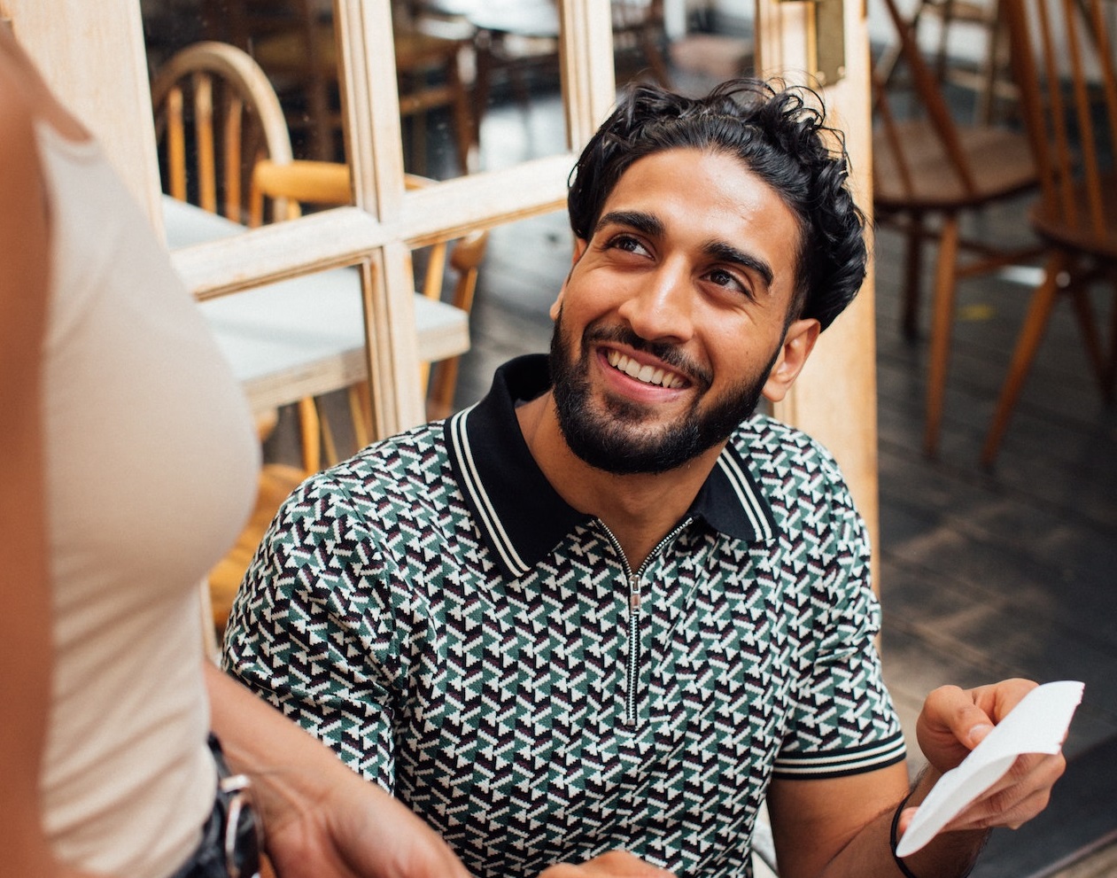 Man smiling at waitress in restaurant while paying the bill.