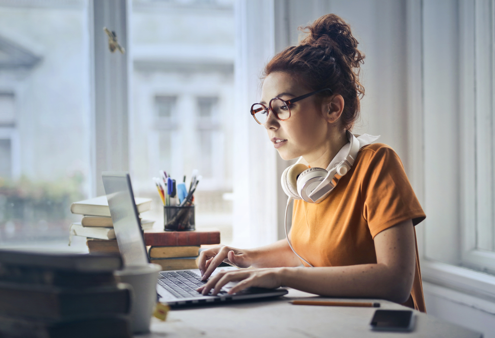 Young woman  in orange t-shirt working on a laptop