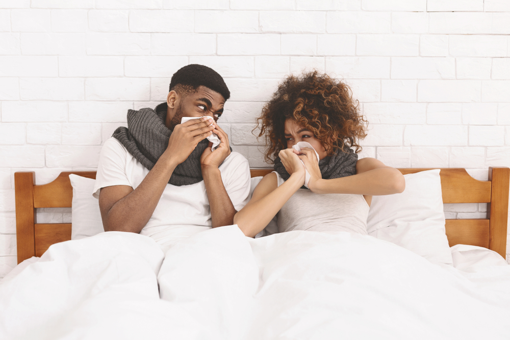 Young african-american couple sneezing into paper napkins